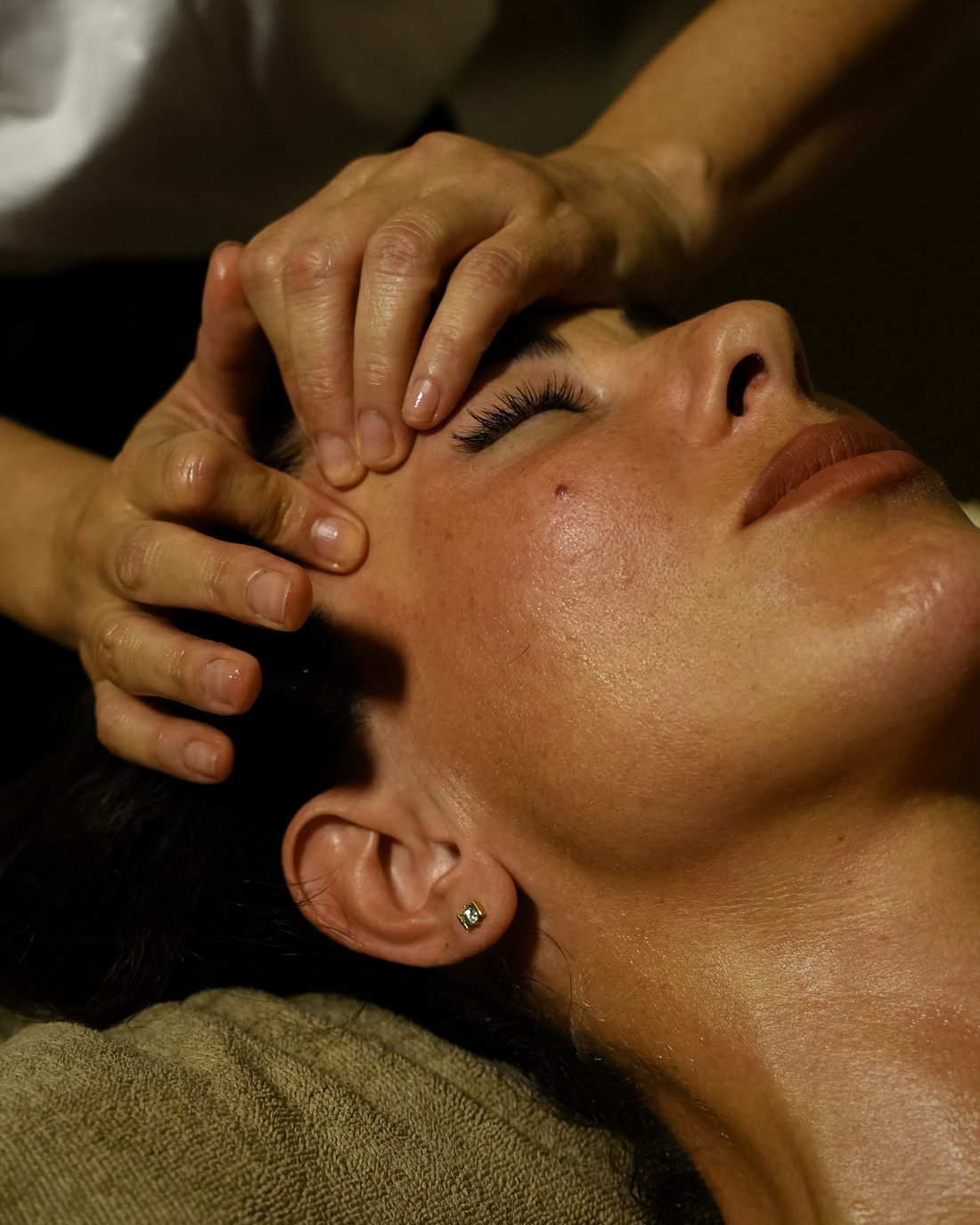 A therapist's hands working a client's brow and temples