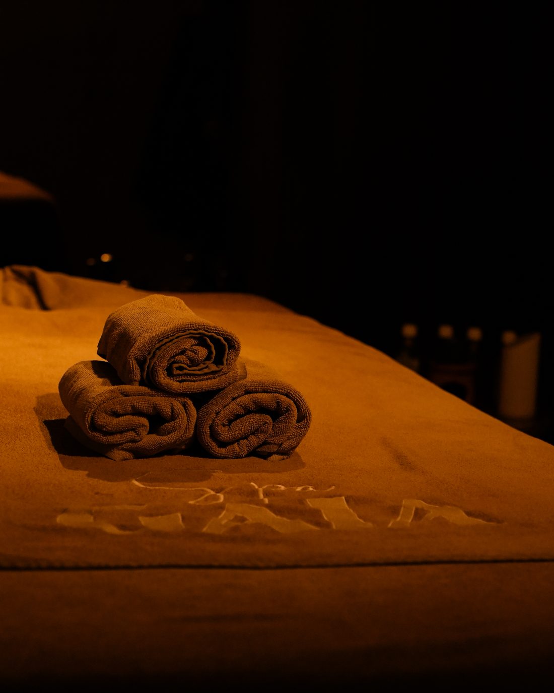 Rolled towels on a Spa Gaia treatment table in warm light